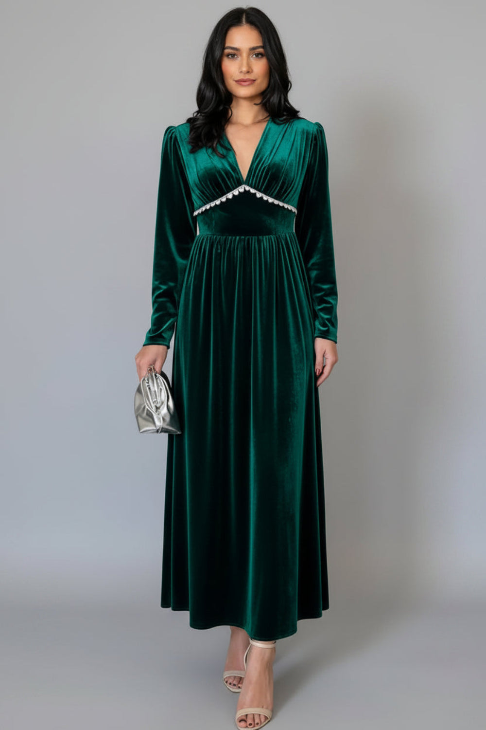 Woman wearing a green velvet dress on a gray background