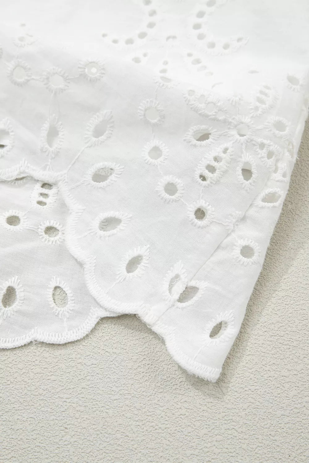 Close-up of a white lace fabric with a textured background