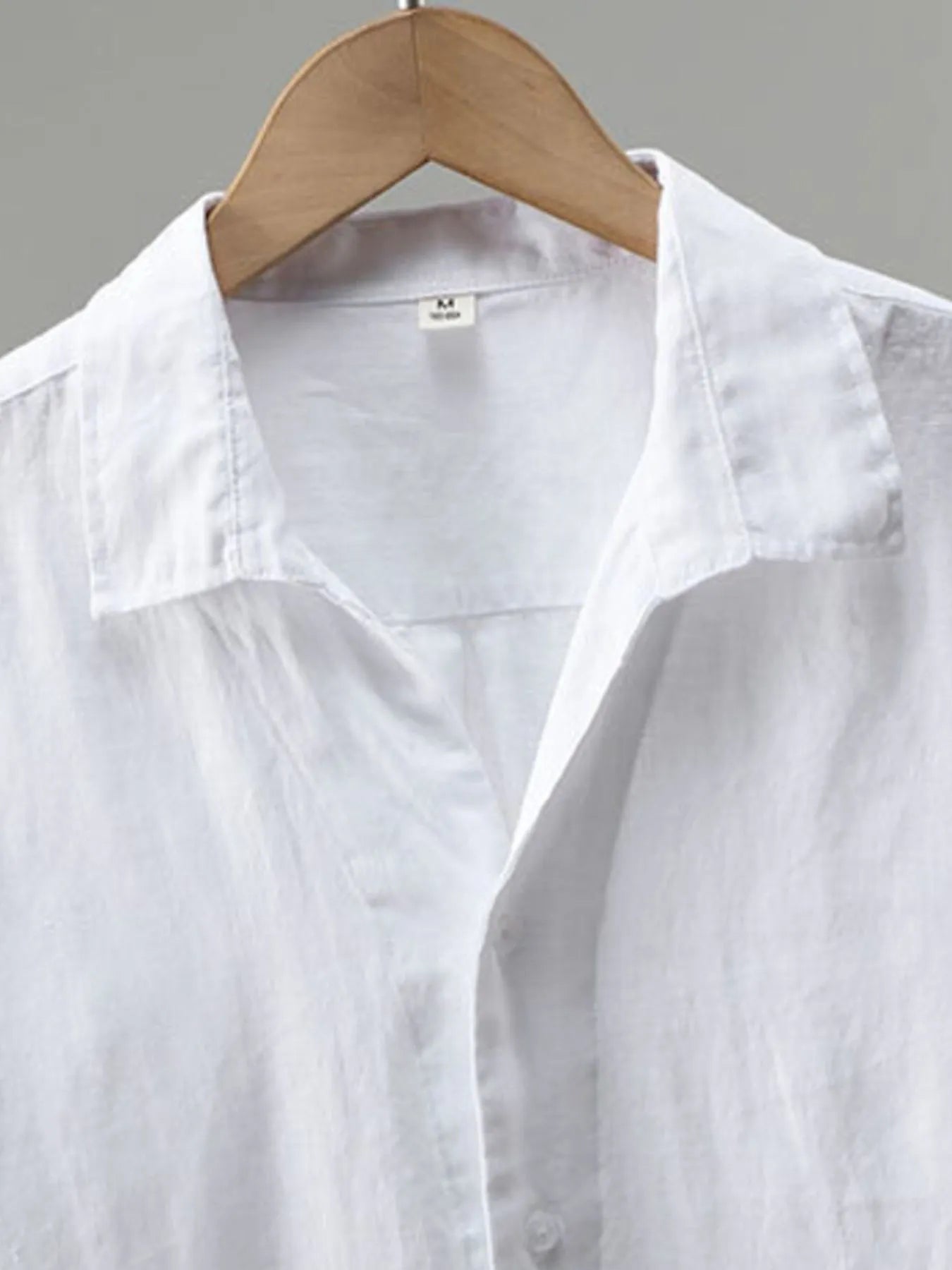 White shirt on a wooden hanger against a gray background