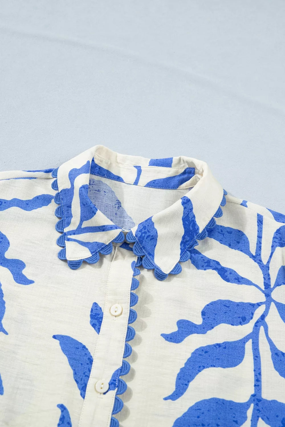 Close-up of a white shirt with blue floral patterns on a light blue background
