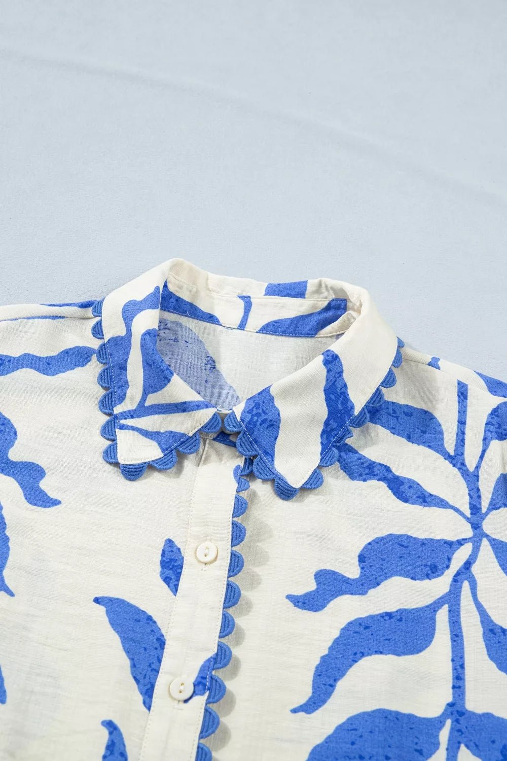 Close-up of a white shirt with blue floral patterns on a light blue background