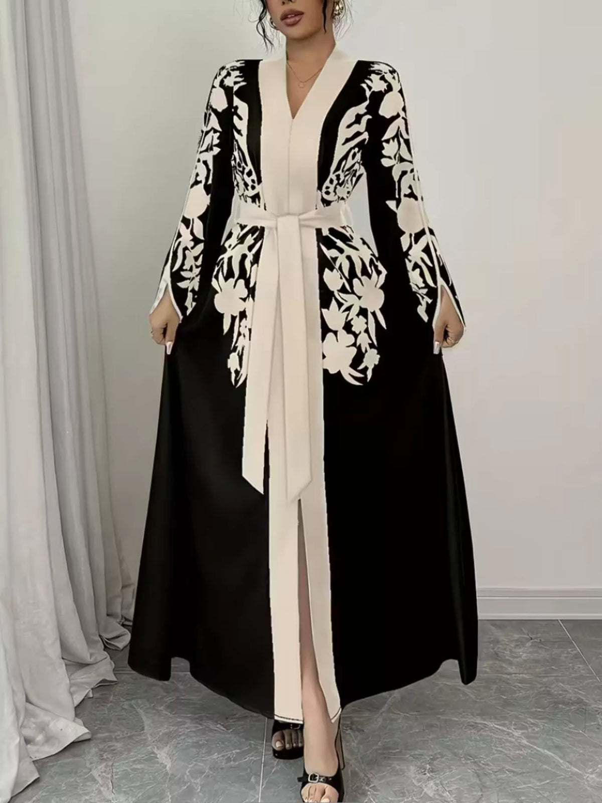 Woman wearing a black and white floral abaya in a minimalistic setting
