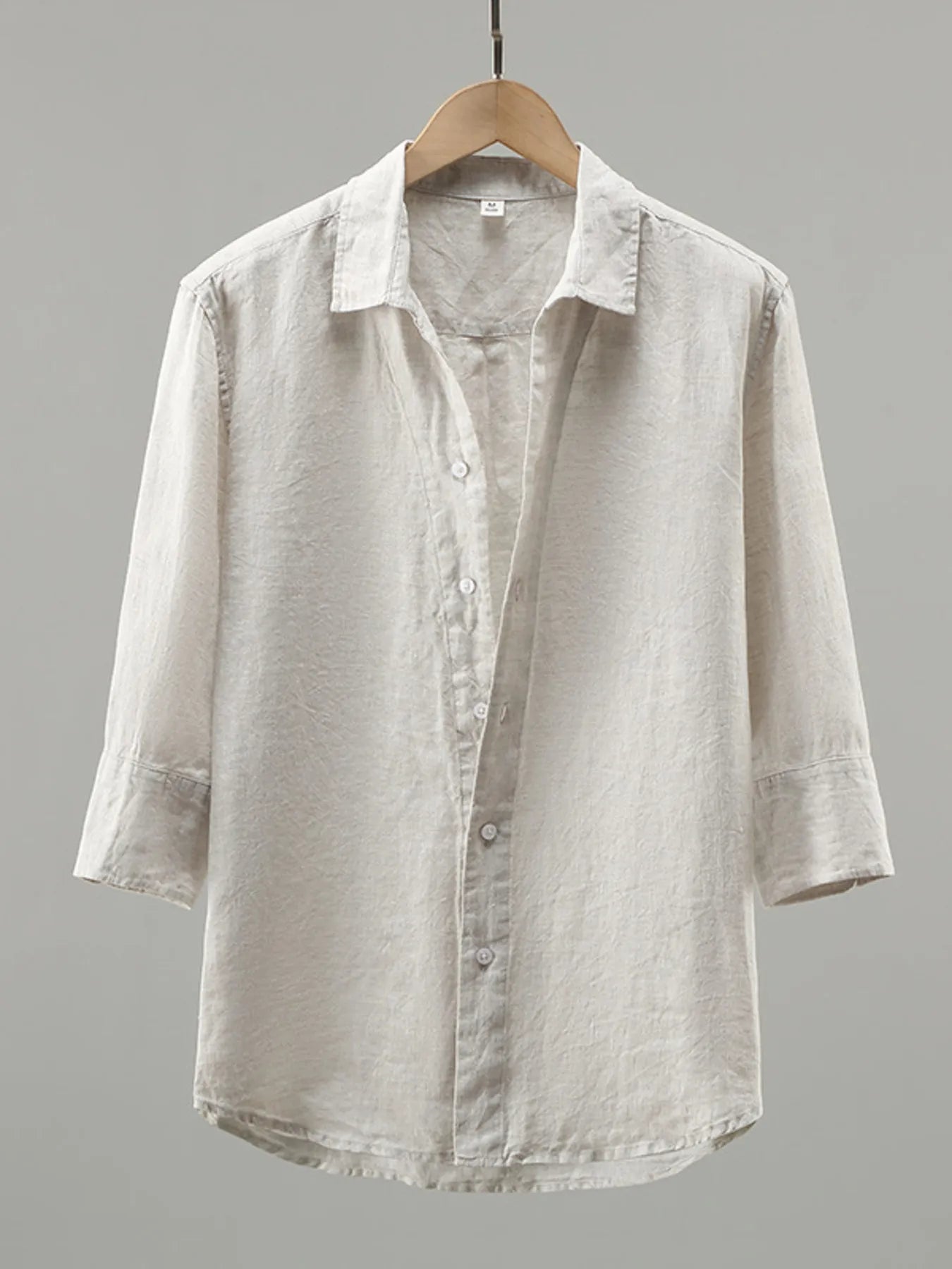 Light gray shirt on a wooden hanger against a gray background