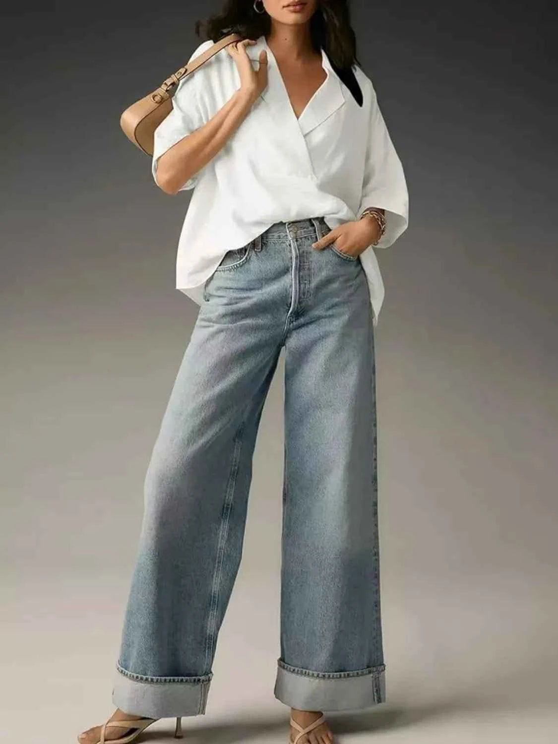 Woman wearing a white shirt and light blue jeans against a gray background