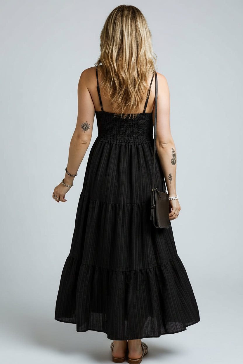 Person wearing a black dress with tattoos on arms against a dark background