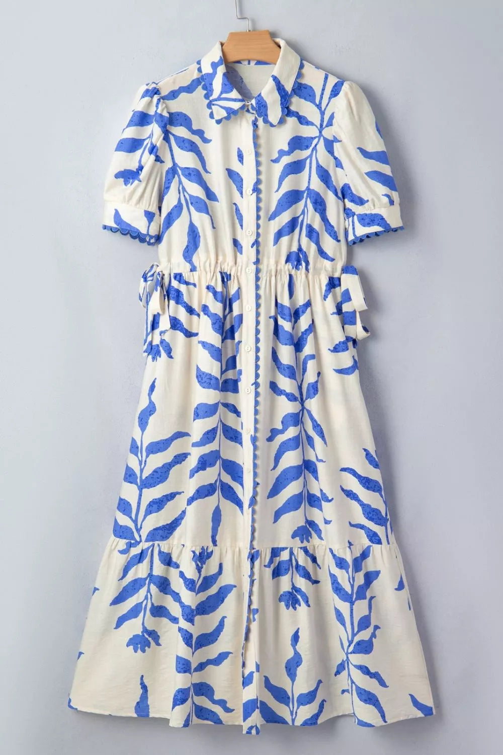 White dress with blue leaf pattern on a gray background