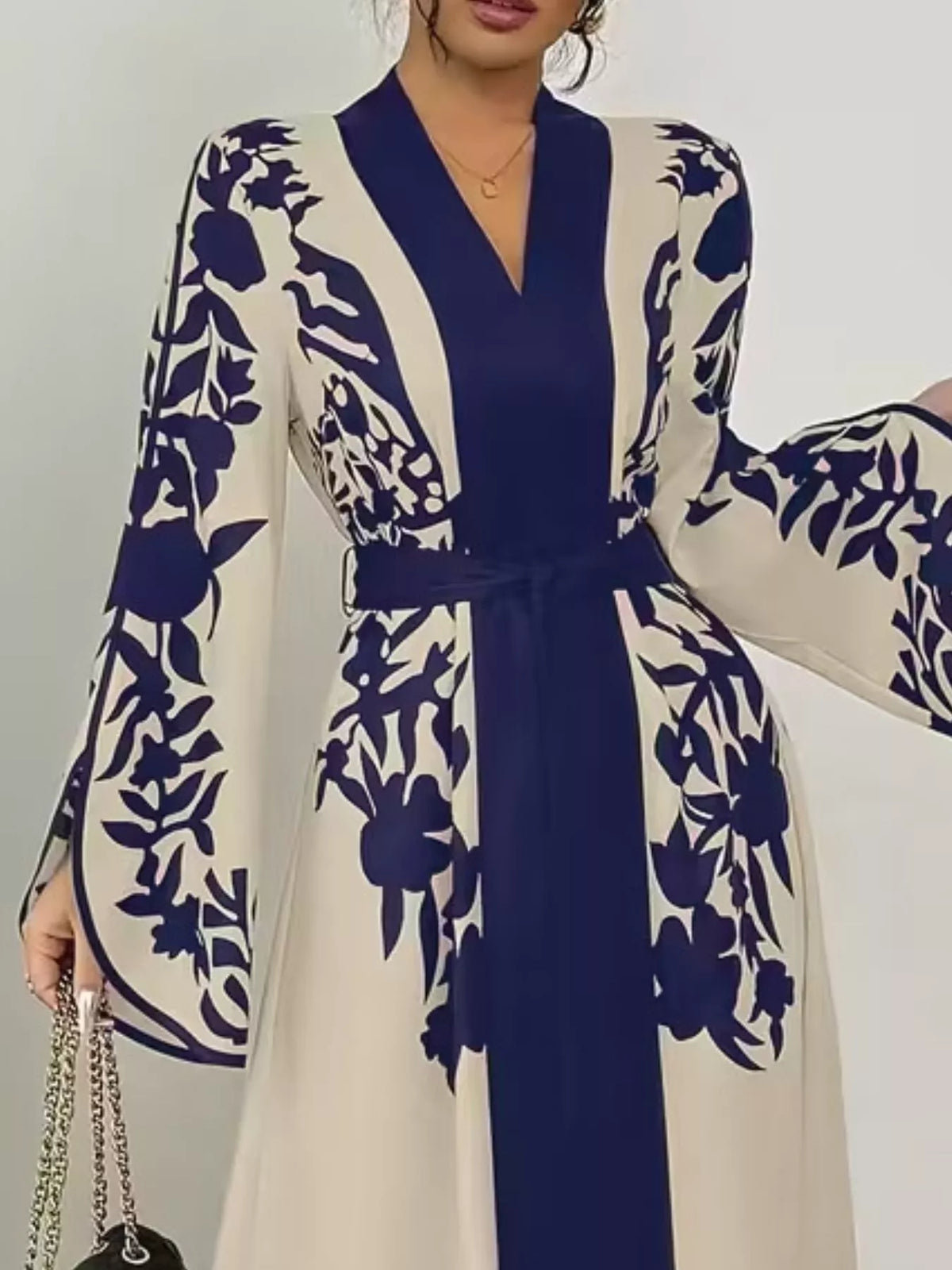 Woman wearing a blue and white floral dress with a belt against a neutral background