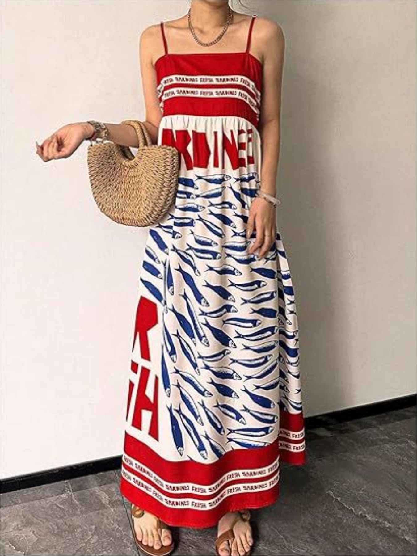 Woman wearing a red, white, and blue dress with a patterned design, holding a straw bag.