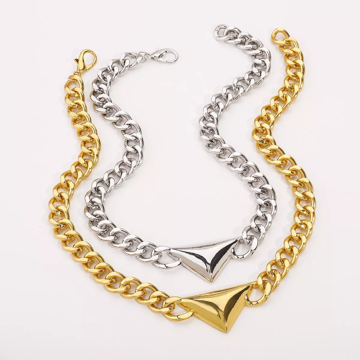 Two chain necklaces, one gold and one silver, on a light gray background.