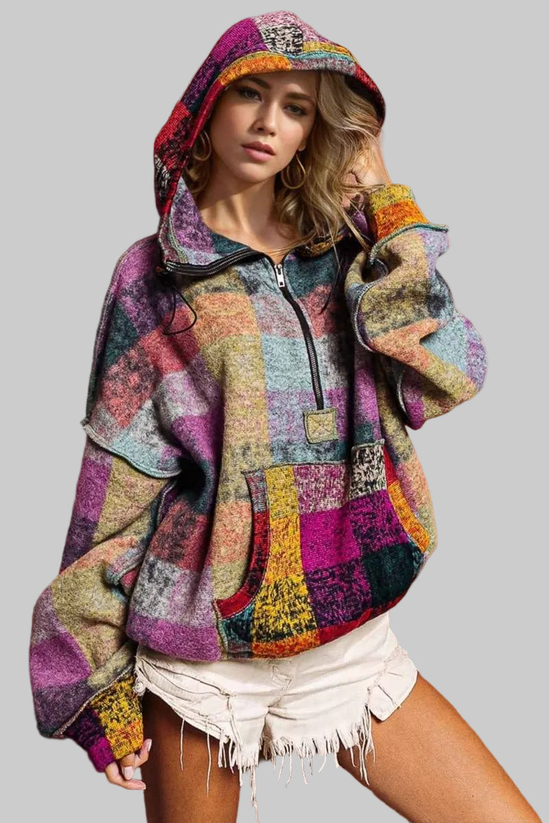 Woman wearing a colorful patchwork hoodie against a brown background