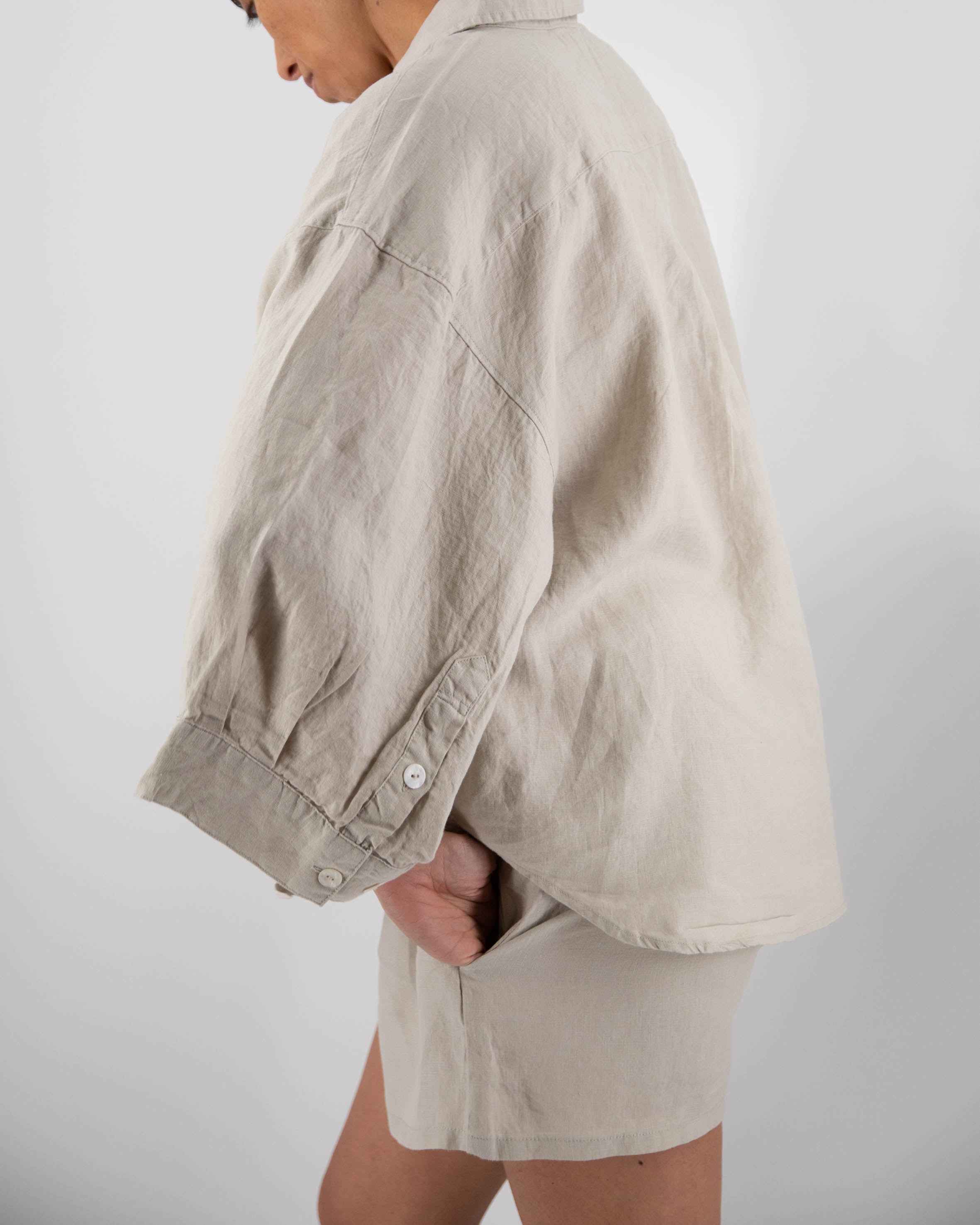 Person wearing a beige jacket and shorts on a plain background