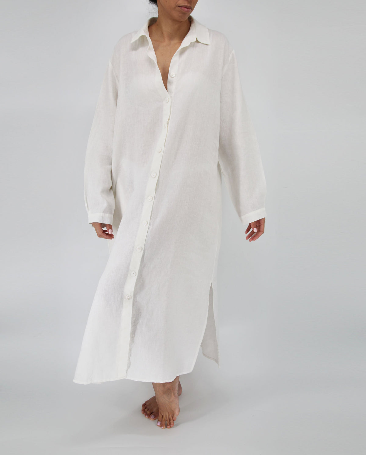 Person wearing a long white shirt on a plain background