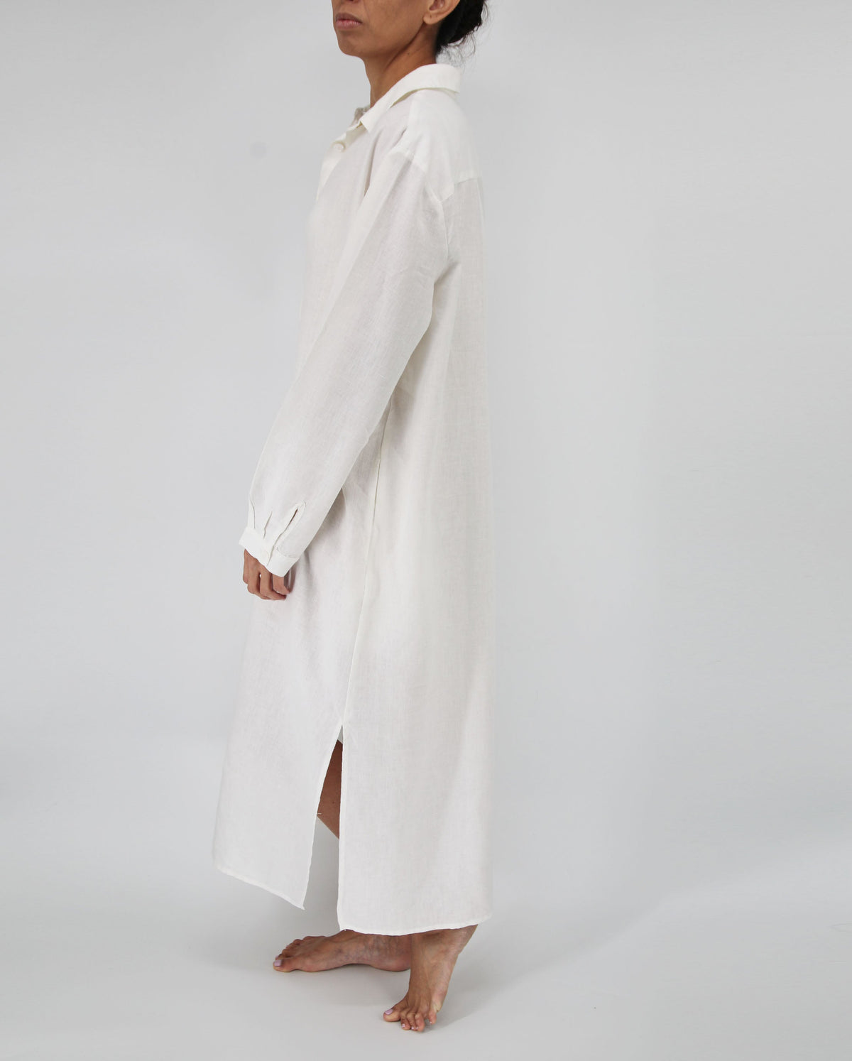 Person wearing a long white coat on a plain background