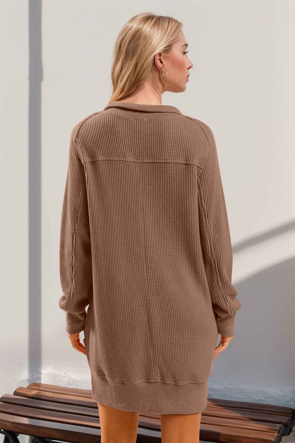 Woman wearing a tan textured A-line mini dress with long sleeves and round neck, Boho Littles Edit collection.