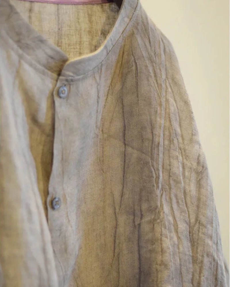 Light brown shirt with buttons on a plain background