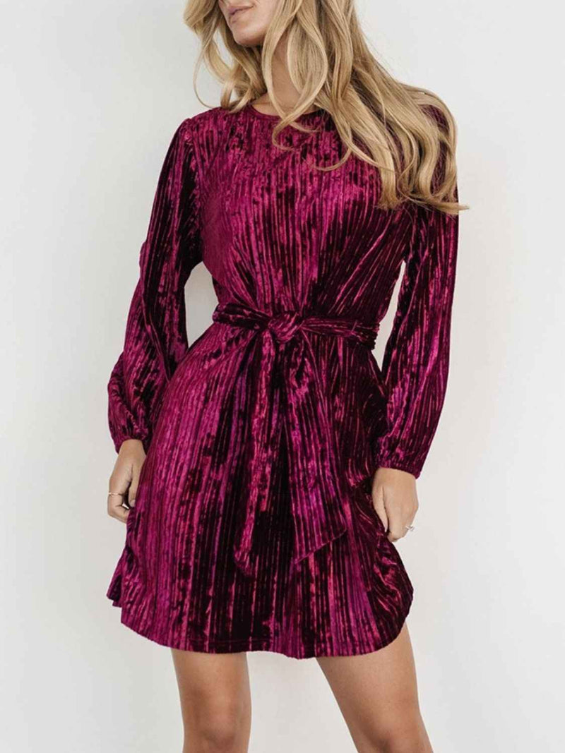 Woman wearing a vibrant pink velvet dress against a white background