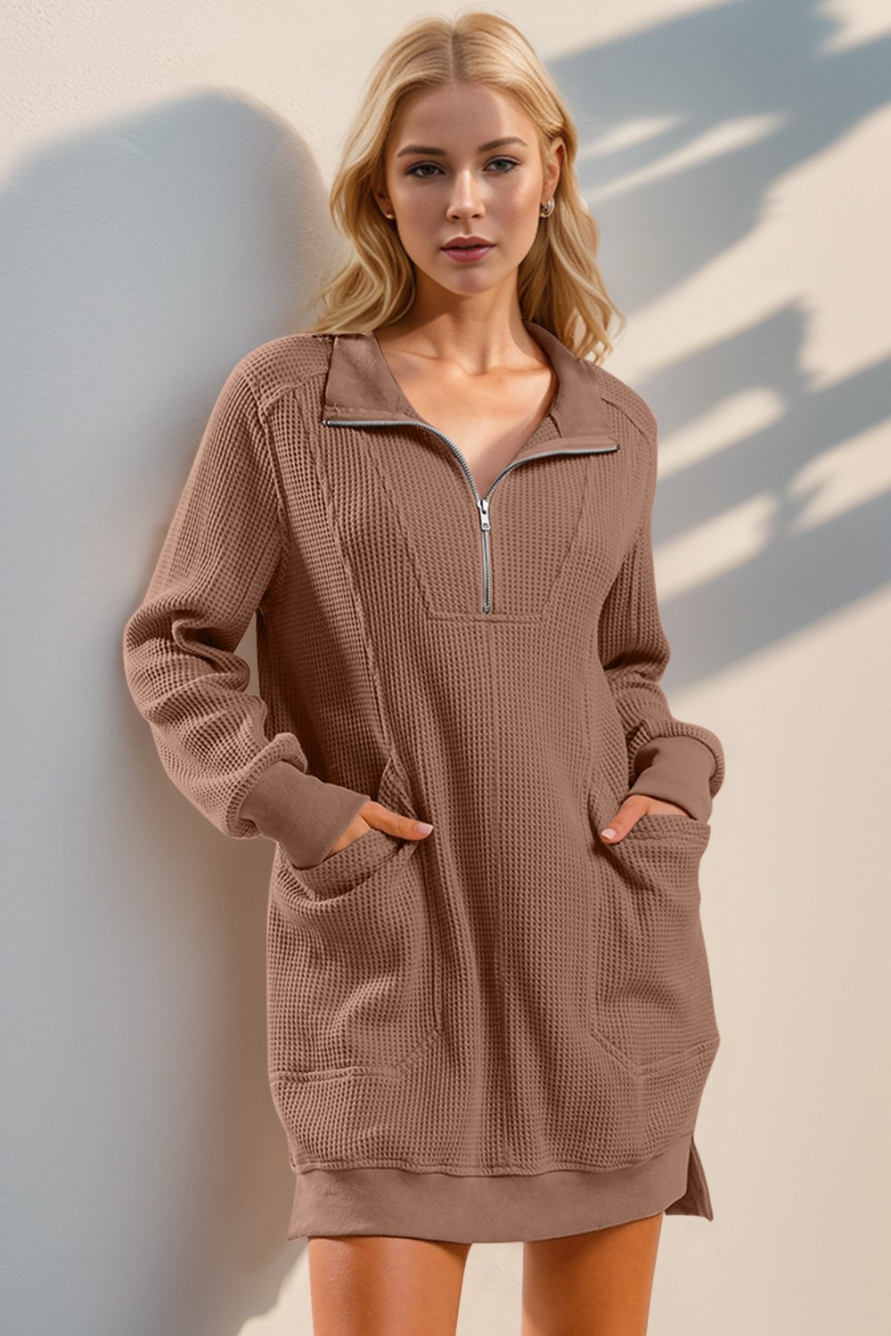 Woman wearing a brown zip-up sweatshirt dress against a neutral background