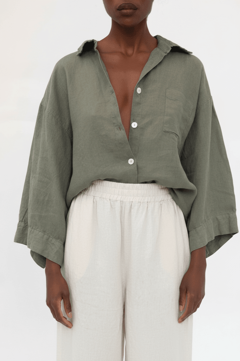 A model wearing an olive green linen button-down shirt with wide sleeves and white linen trousers, shot against a plain white background.