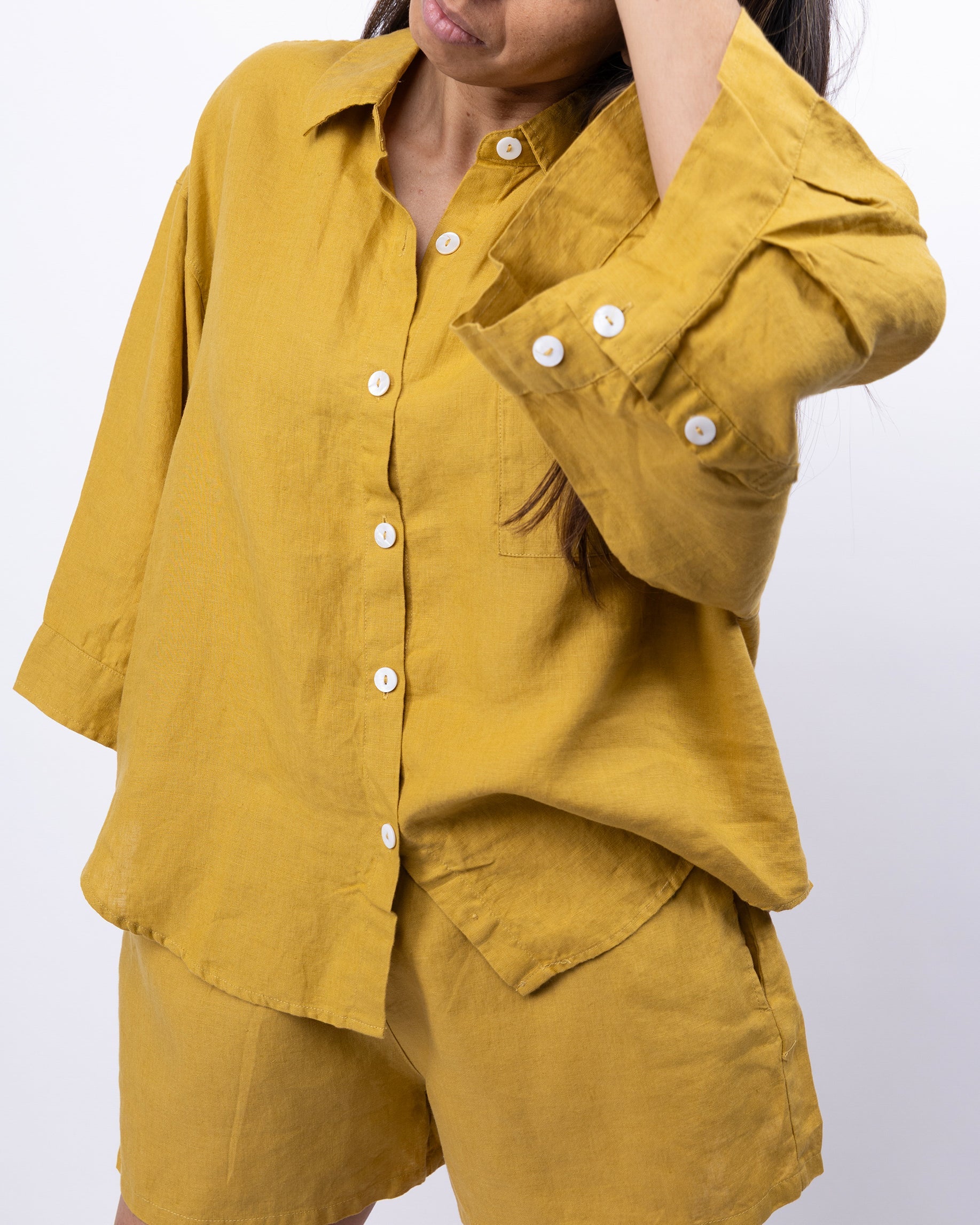 Person wearing a mustard yellow outfit with button details on a white background