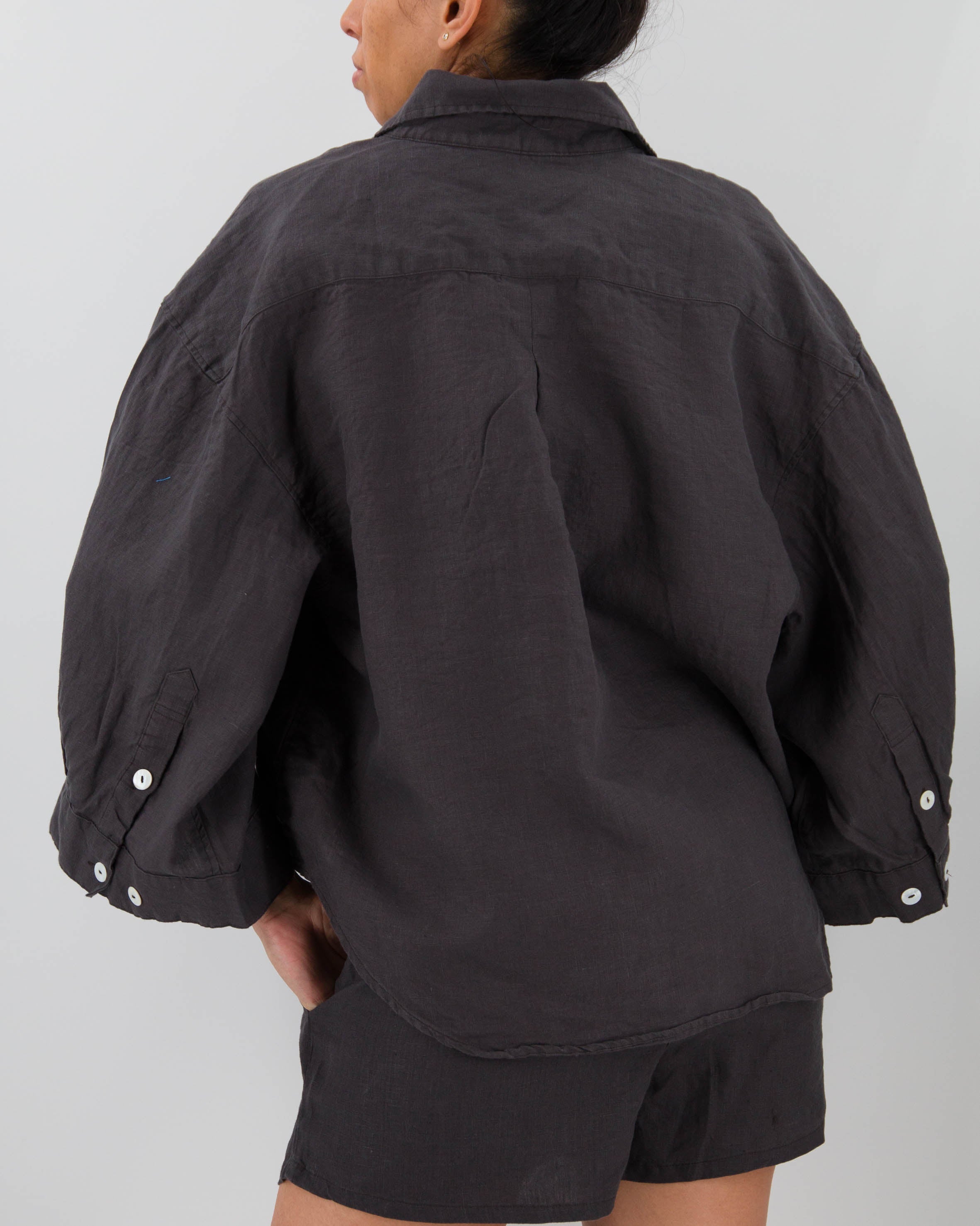 Person wearing a black jacket and shorts on a plain background