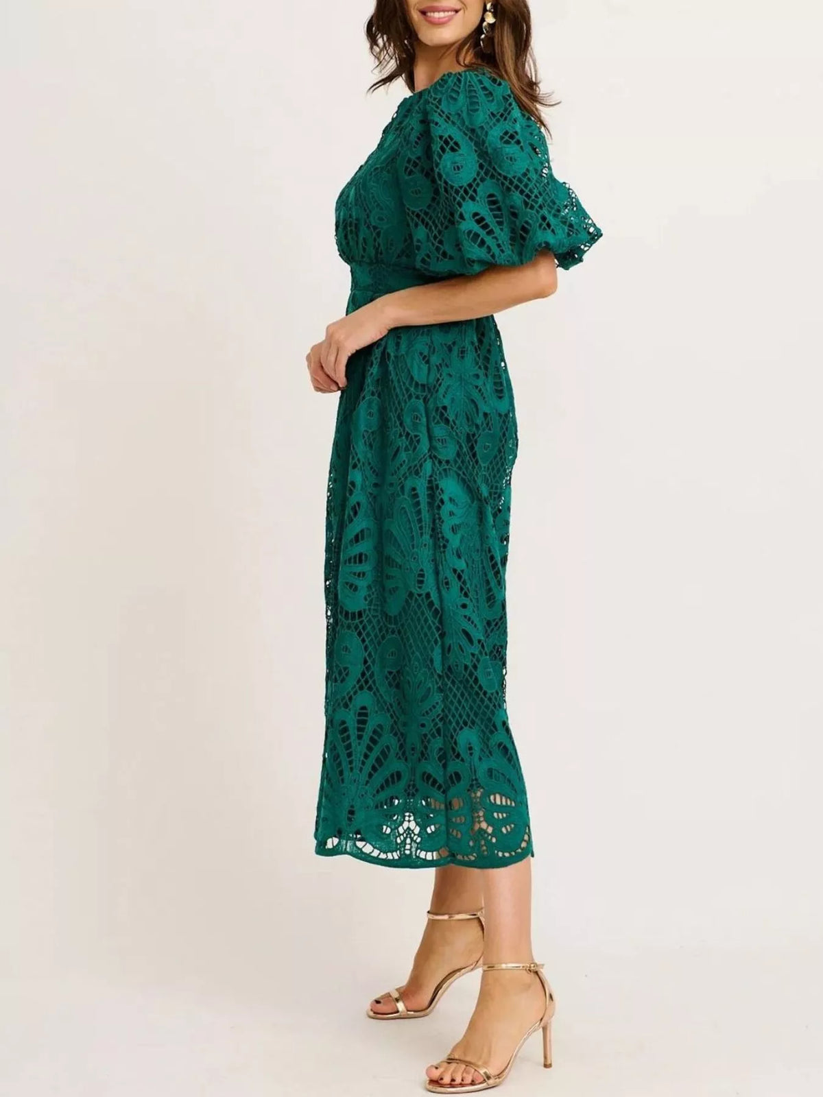 Woman wearing a green lace dress on a plain background
