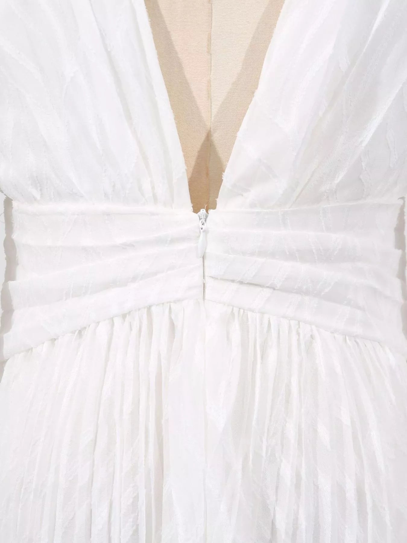 Close-up of a white dress with a deep neckline and bow detail.