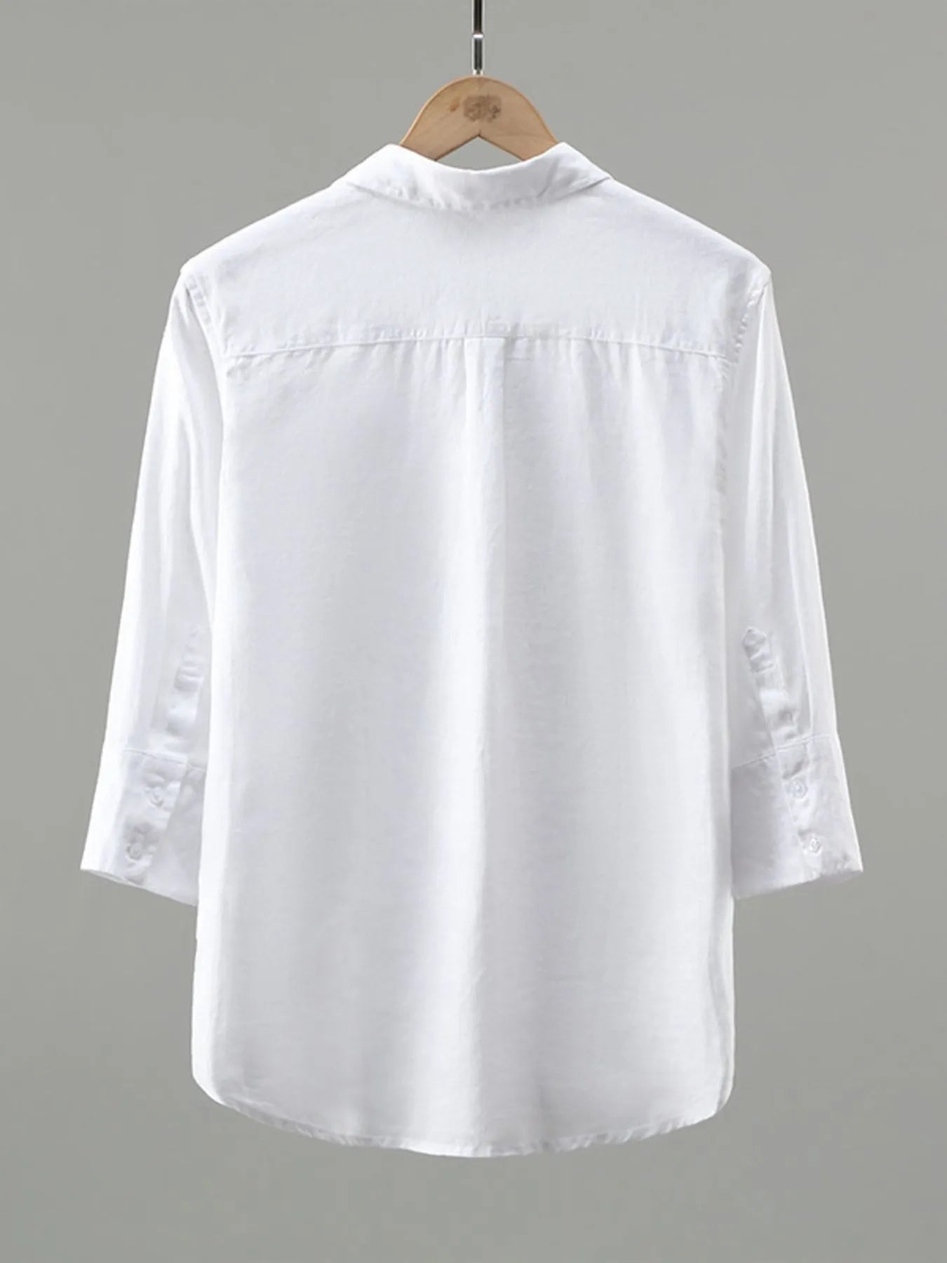White shirt on a hanger against a gray background
