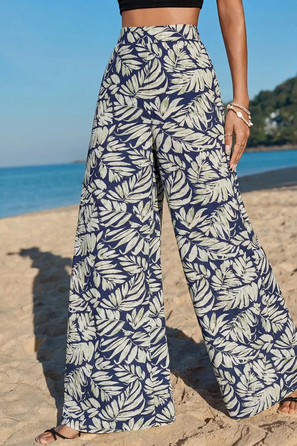 Person wearing blue and white leaf-patterned pants on a beach.