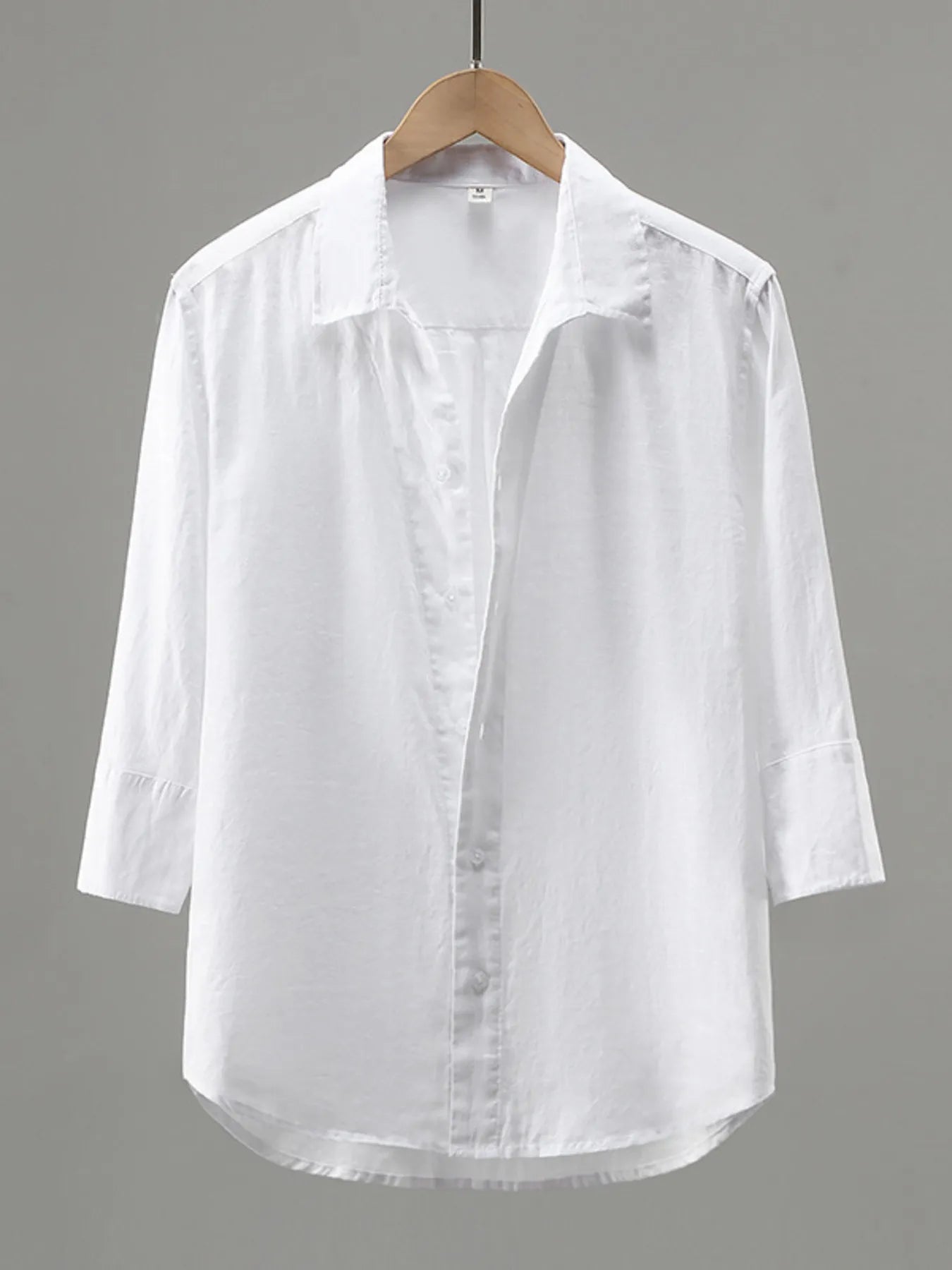 White shirt on a wooden hanger against a gray background