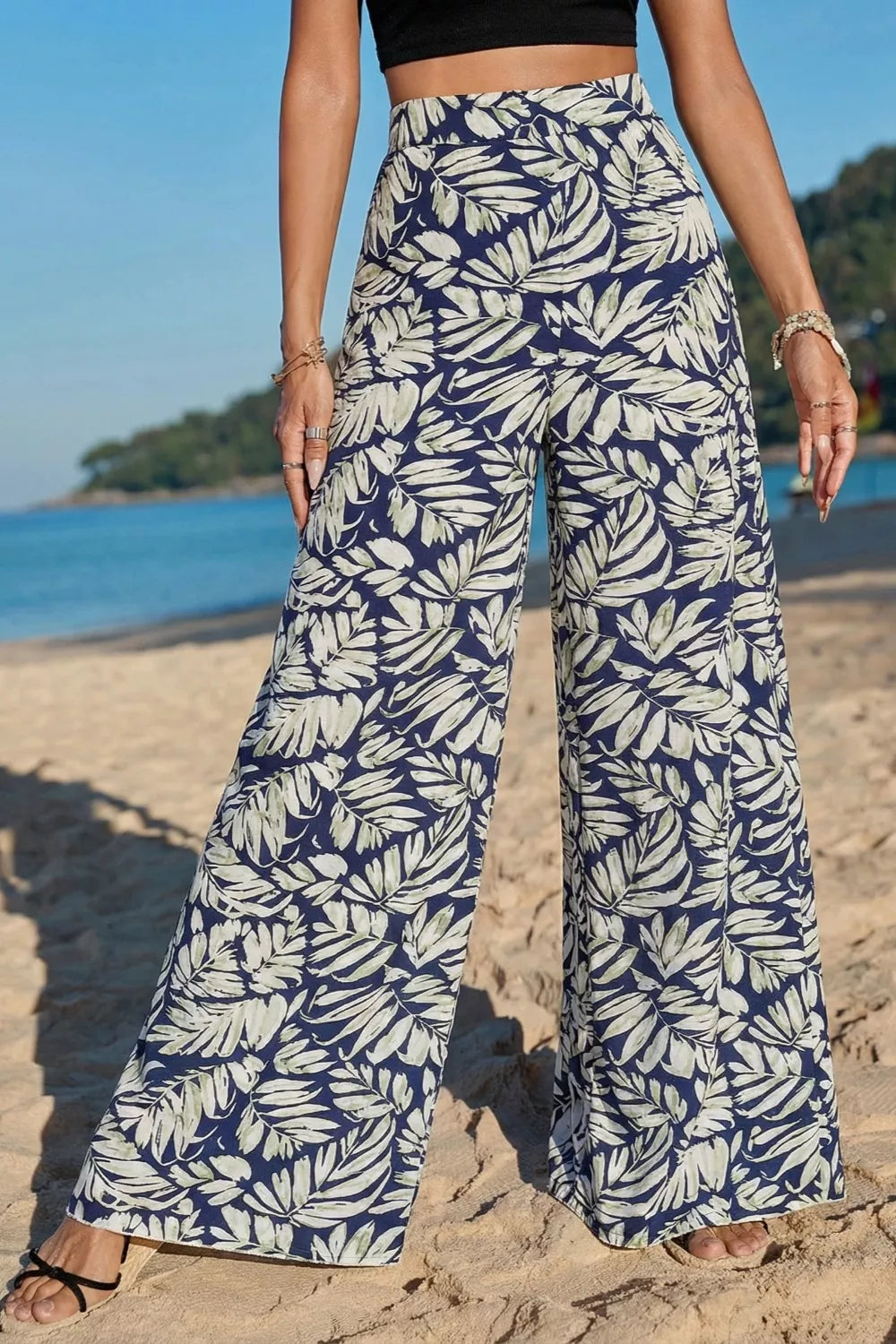 Person wearing blue and white leaf-patterned pants on a beach.