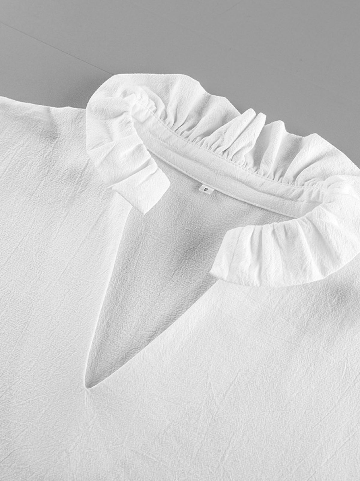 White ruffled collar on a light gray background
