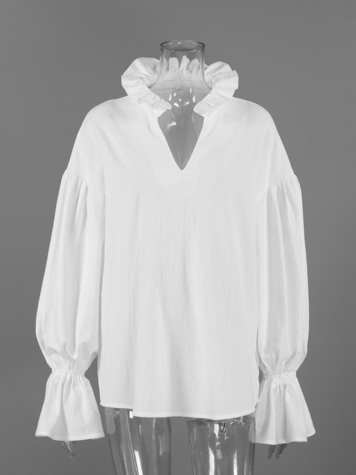 White blouse with ruffled collar on a mannequin against a gray background