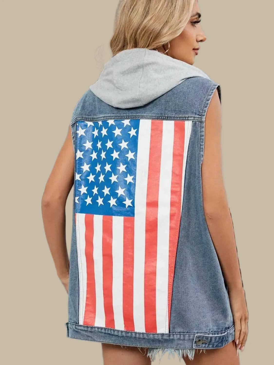 Person wearing a denim vest with an American flag design outdoors.