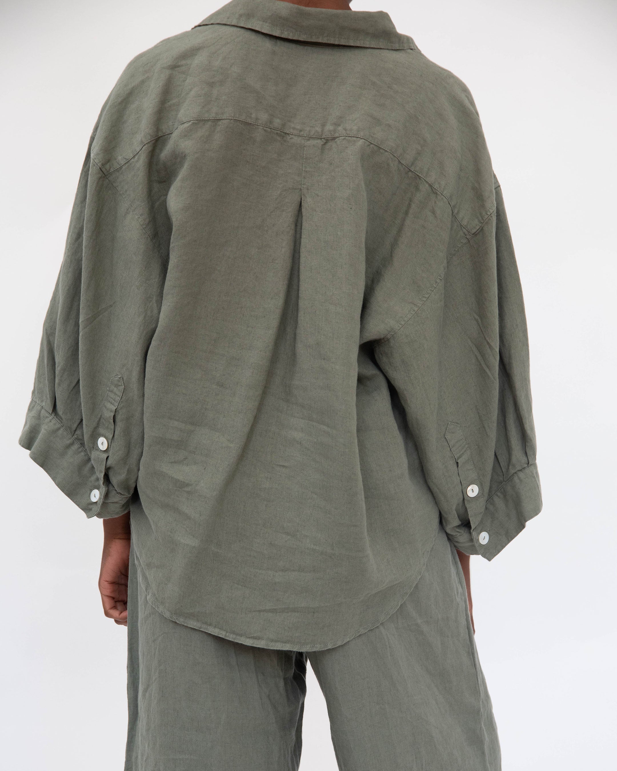 Person wearing a green shirt and pants on a white background