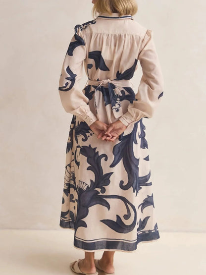 Person wearing a long dress with blue floral patterns on a plain background