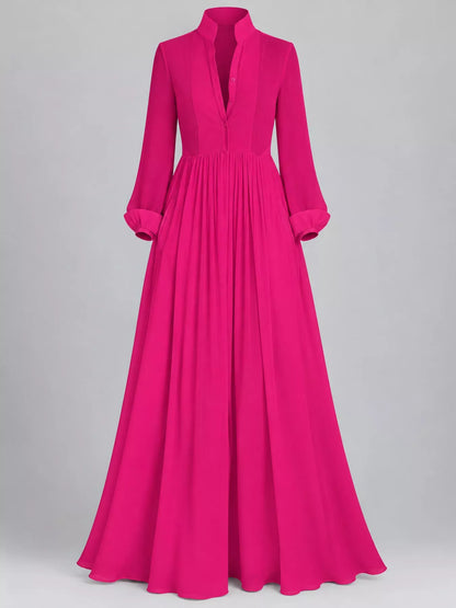 A bright fuchsia pink long-sleeve maxi dress with a high mock neck, split V-neckline, and a pleated skirt, shown on a neutral gray background.