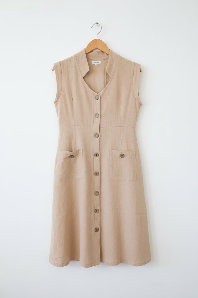 Beige dress with buttons on a hanger against a neutral background