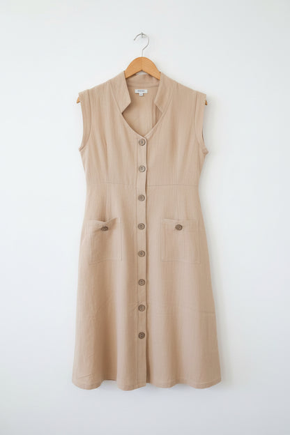Beige dress with buttons on a hanger against a neutral background