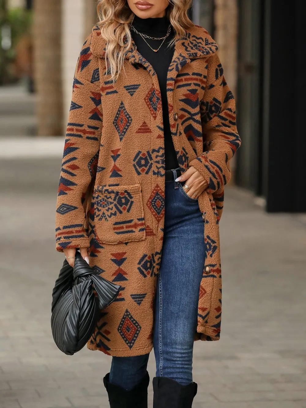 Woman wearing a patterned coat with jeans and boots on a street.