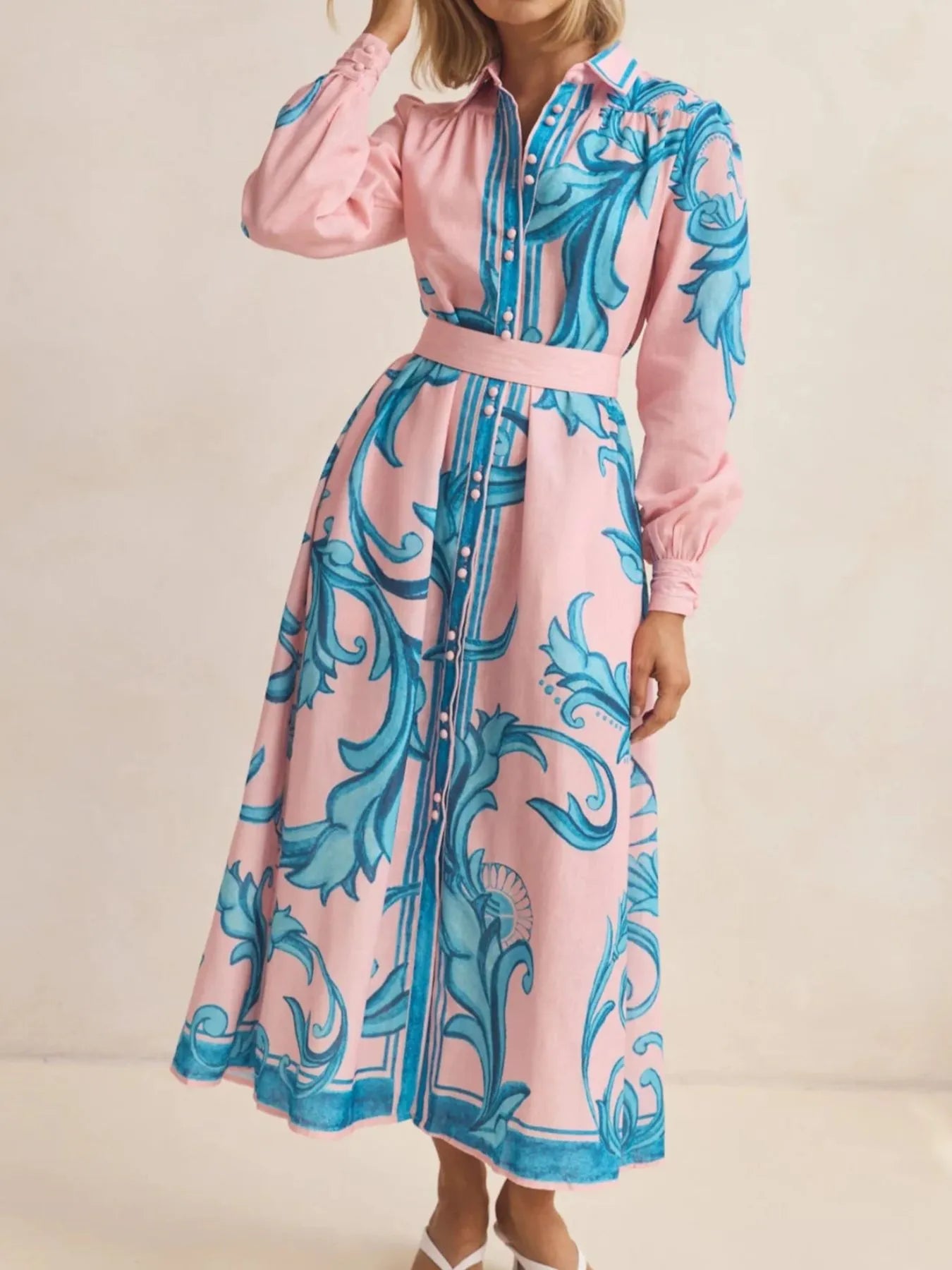 Pink dress with blue floral pattern worn by a person on a beige background