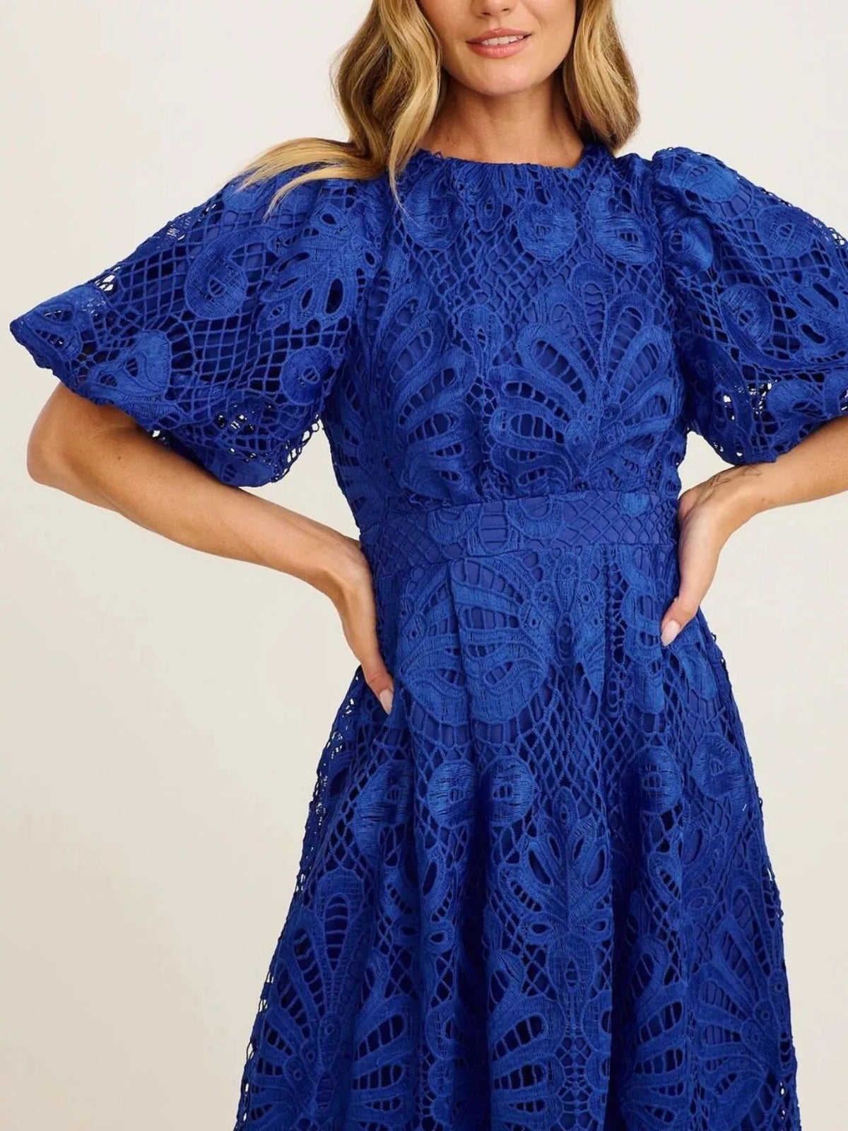 Blue lace dress worn by a model on a plain background