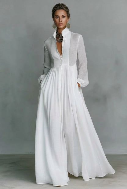 A model posing in a white long-sleeve button-front maxi dress featuring a V-neckline, Victorian-inspired sleeves, and a relaxed, flowy silhouette.