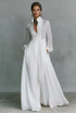 A model posing in a white long-sleeve button-front maxi dress featuring a V-neckline, Victorian-inspired sleeves, and a relaxed, flowy silhouette.
