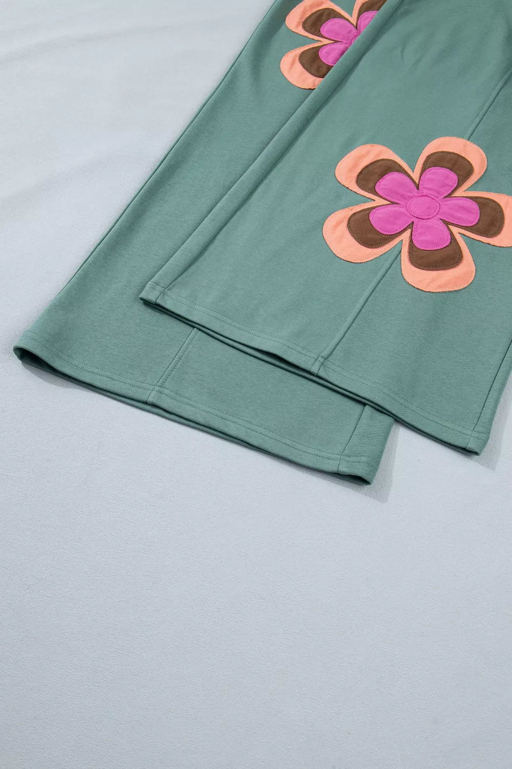 Green fabric with pink and orange floral patterns on a light gray background