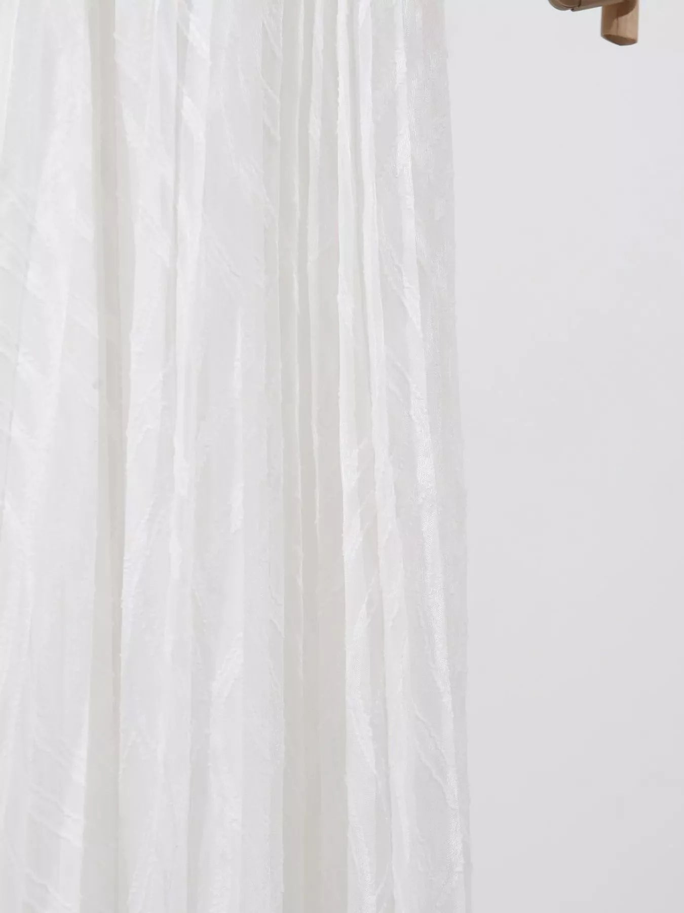 Close-up of white fabric with a subtle pattern on a light background