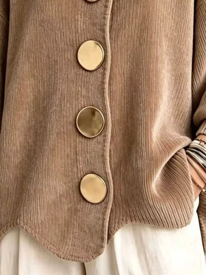 Close-up of a taupe corduroy cardigan with large round gold-tone buttons, worn over white bottoms.