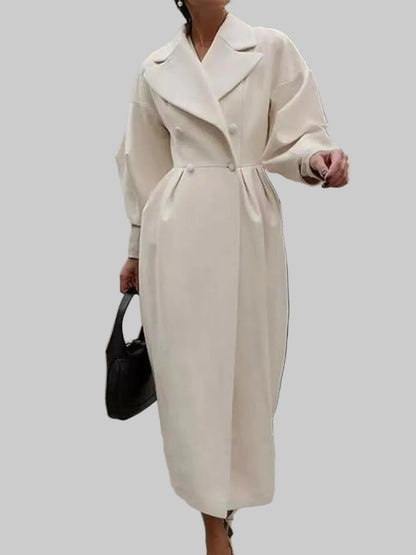 Person wearing a long beige coat walking outdoors on a city street.