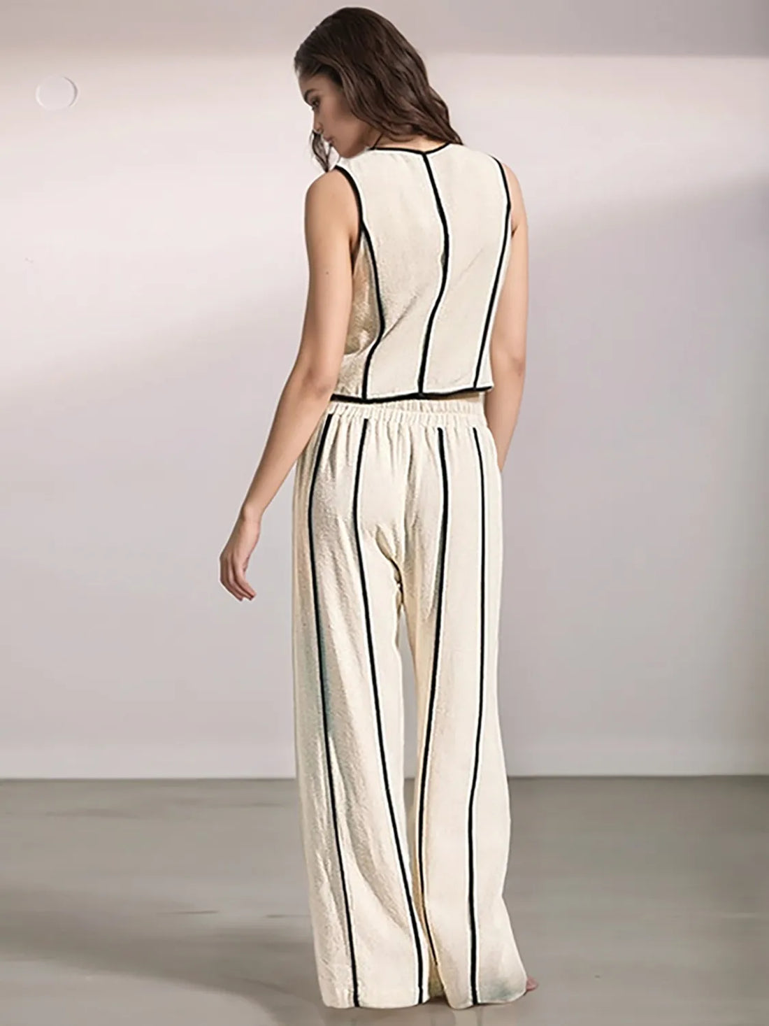 Woman wearing a white jumpsuit with black stripes on a plain background