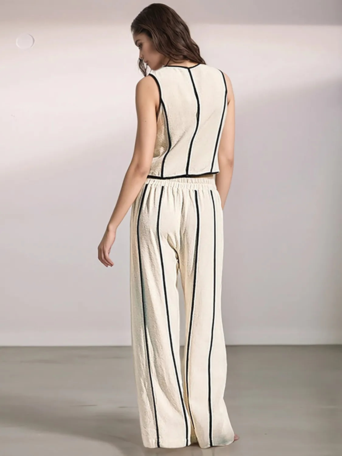 Woman wearing a white jumpsuit with black stripes on a plain background
