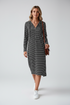 A woman modeling a black and white horizontally striped long-sleeve midi dress with a half-zip neckline, paired with white sneakers and a brown shoulder bag, against a light gray studio background.